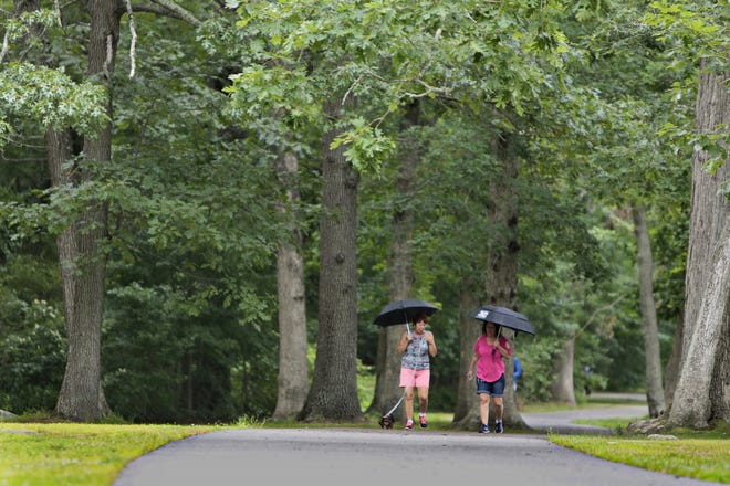 Two women don't let the rainfall stop them from walking around Buttonwood Park in New Bedford in August. [ PETER PEREIRA/THE STANDARD-TIMES/SCMG ]