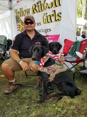 Former Ellwood City resident Dennis Morida served for more than 20 years in the Army National Guard in Iraq, Bosnia and Afghanistan. But now he has started a program to help train and donate service dogs such as the ones in the picture for veterans and first responders. Here Morida is at the Ellwood City Arts, Crafts, Food and Entertainment Festival helping raise money for the Yellow Ribbon Girls, who send supplies to troops overseas. [Submitted]