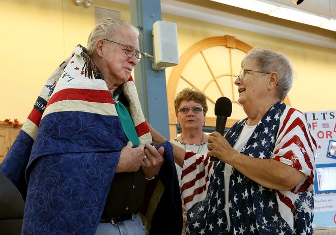 Bill Durbin, a Korean War veteran with the U.S. Air Force, left, is emotional after having his Quilt of Valor draped around his shoulders with Mary Johnson, right, and Joyce Burnham, center, Saturday morning in the Domestic Arts building at the Kansas State Fair. [Sandra J. Milburn/HutchNews]