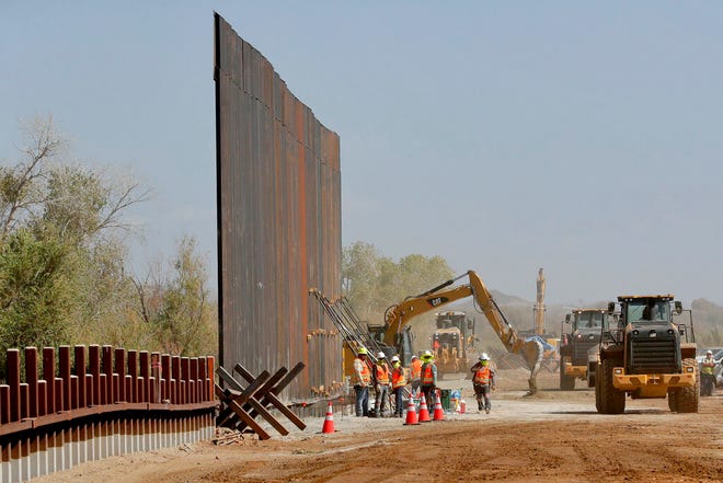 Government contractors erect a section of Pentagon-funded border wall along the Colorado River, Tuesday, Sept. 10, 2019 in Yuma, Ariz. The 30-foot high wall replaces a five-mile section of Normandy barrier and post-n-beam fencing, shown at left, along the the International border that separates Mexico and the United States. Construction began as federal officials revealed a list of Defense Department projects to be cut to pay for President Donald Trump's wall. [ MATT YORK / AP ]