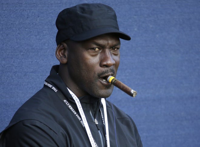 Basketball legend Michael Jordan smokes a cigar while watching the fourball match on the first day of the Ryder Cup golf tournament, at Gleneagles, Scotland, Friday, Sept. 26, 2014. (AP Photo/Matt Dunham)