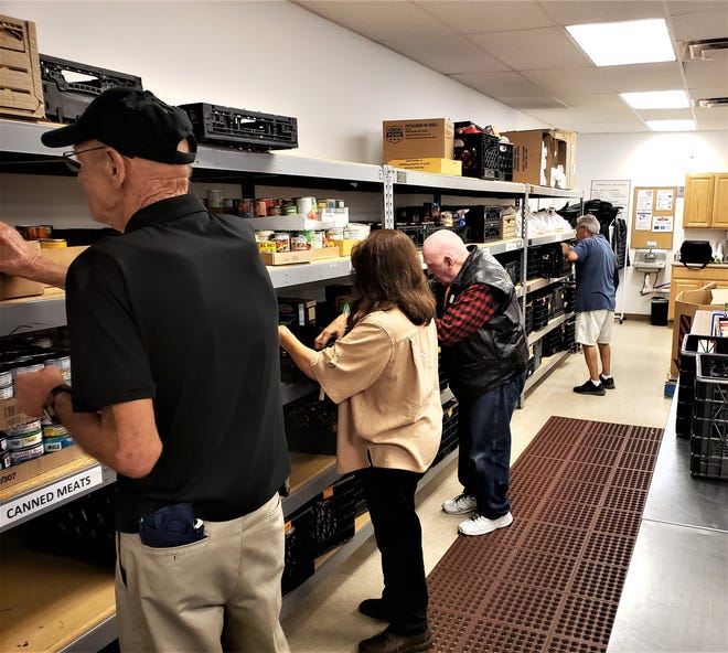 At Pueblo Cooperative Care Center, volunteers, left to right, Robert Hunt, Trini Muniz, Joe Thompson and David Chavez stock shelves on Monday. The care center will benefit from next month's "Feeding the 5,000" food drive. [COURTESY PHOTO]
