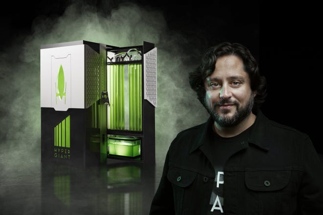 The Eos bioreactor, an algae growing bioreactor cube by Hypergiant Industries, is designed to fit into offices and efficiently remove carbon from the atmosphere. Pictured with the bioreactor is Hypergiant CEO Ben Lamm. 

[Courtesy Hypergiant Industries]