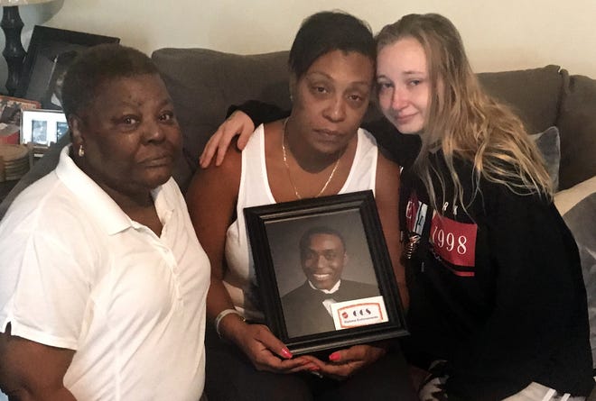 From left, Debbie McClain, Keya Parsons and Brittany Vogel pose with a picture of Highland Tech graduate Raishon Peterman Jr., who died in a car wreck on Friday in Jackson County, North Carolina. He was a senior at Western Carolina University. [Adam Lawson/Gaston Gazette]