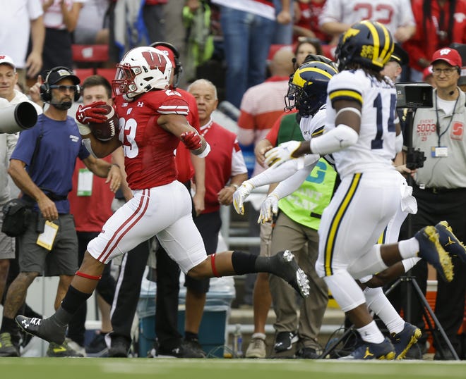Wisconsin running back Jonathan Taylor make a first-down run against Michigan defensive back Brad Hawkins and defensive back Josh Metellus on Saturday in Madison, Wis. [AP Photo/Andy Manis]