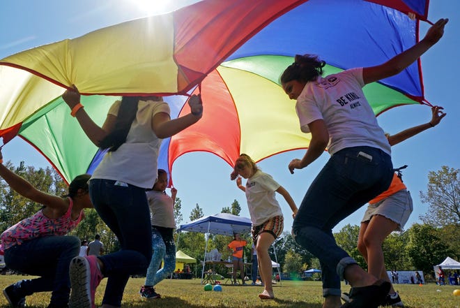 Kids play with a parachute at the Olneyville Multicultural Festival, held in Providence's Riverside Park on Saturday. [The Providence Journal / Sandor Bodo]
