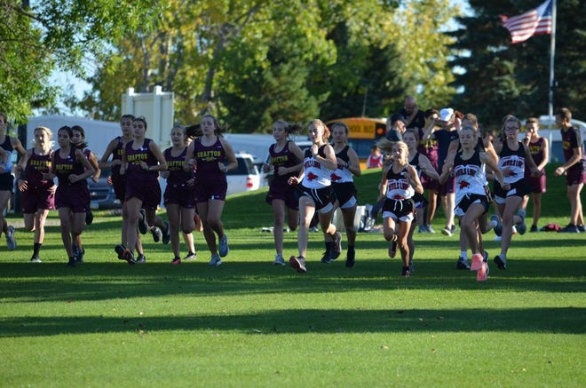 Devils Lake girls are seen alongside Grafton at the start of a cross country race Monday, Sept. 23, 2019 in Langdon.