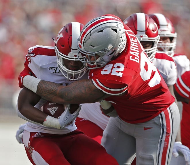 Ohio State defensive tackle Haskell Garrett wraps up Miami running back Tyre Shelton in the first quarter Saturday. Garrett was named a co-defensive player of the game. [Eric Albrecht/Dispatch]