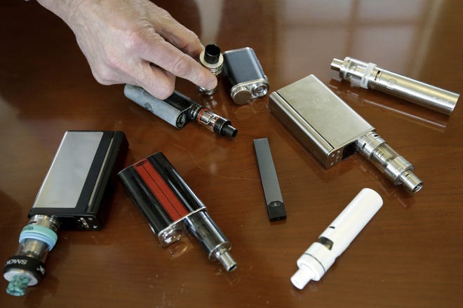 In this April 10, 2018, photo, a high school principal displays vaping devices that were confiscated from students at a school in Massachusetts. On Friday, the Centers for Disease Control and Prevention said 805 confirmed and probable cases have been reported to have a vaping-related breathing illness, and the death toll has risen to 12. [AP Photo/Steven Senne]