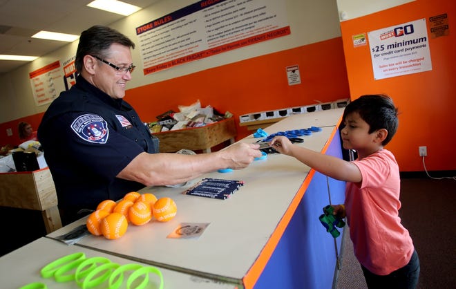 James Willard of Shelby Police Department gives Jacob Castillo, 7, a police sticker at Everything Must Go's Back the Badge event on Saturday. [Brittany Randolph/The Star]