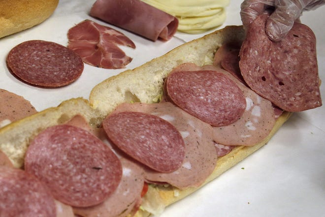 In this June 5, 2014, file photo, a man makes a submarine sandwich with mortadella, cooked salami, ham, Genoa salami and sweet capicola at a delicatessen in Massachusetts. An international team of researchers is questioning the advice to limit red and processed meats, saying the link to cancer and heart disease is weak. Their conclusions were swiftly attacked by a group of prominent U.S. scientists who tried to stop publication of the research, arguing it sends the wrong message. [ELISE AMENDOLA/ASSOCIATED PRESS]