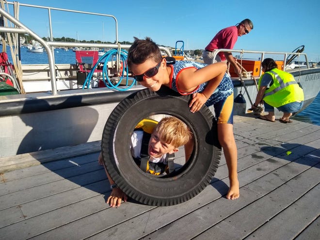 Kai Kovar (bottom) and Ethan Cook pose with a discarded tire they picked up during the cleanup.

[Courtesy photo]