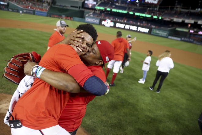 Washington Nationals' Juan Soto gets a kiss from his father, Juan Jose Soto, right, after defeating the Milwaukee Brewers 4-3 in a National League wild-card baseball game at Nationals Park, Tuesday, in Washington. [The Associated Press / Andrew Harnik]
