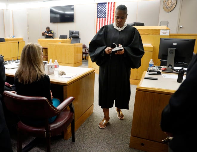 State District Judge Tammy Kemp opens a Bible to John 3:16 before giving it to former Dallas Police Officer Amber Guyger, left, before Guyger left for jail, Wednesday, Oct. 2, 2019, in Dallas. Guyger, who said she mistook neighbor Botham Jean's apartment for her own and fatally shot him in his living room, was sentenced to a decade in prison. (Tom Fox/The Dallas Morning News via AP, Pool)