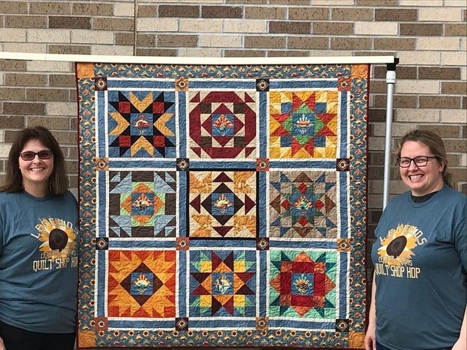 Connie Hart, left, and Annarose White, owners of Beehive Quilt Shop in Wellington, stand by the quilt they made as part of the 2019 Central Kansas Quilt Shop Hop. [Submitted]