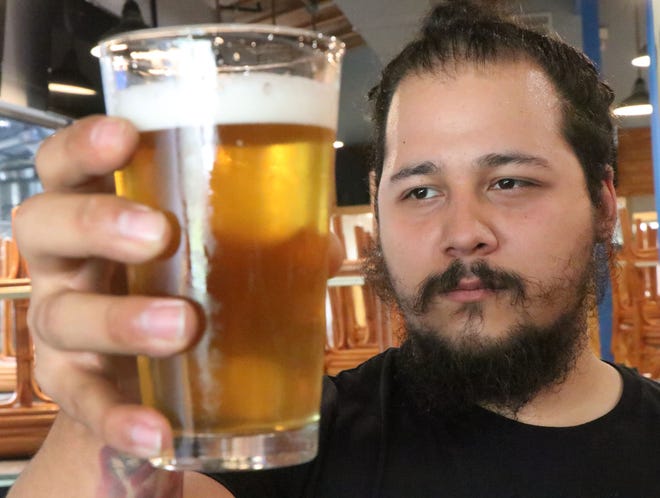 Horus Andersen, the head brewer at Blue Springs Brewing, holds a glass of Trails and Passes, the house cream ale at Orange City's first microbrewery. [News-Journal/David Tucker]