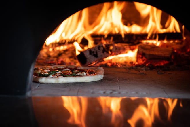 A pizza cooks in the brick oven at Gusto Napoletano on Raeford Road. [Andrew Craft/The Fayetteville Observer]