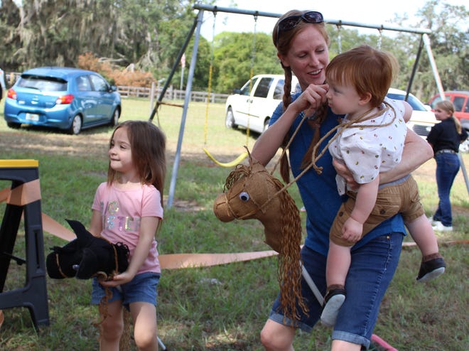 Ellia Campla, 3, of Palmetto, races broomstick ponies with her mom Amy and brother Asher, 1, at the Old Miakka Fall Hootenanny Schoolhouse Benefit on Sunday. The annual event raises money to restore and preserve the 105-year-old one-room school house. [HERALD-TRIBUNE STAFF PHOTO/ TIMOTHY FANNING]