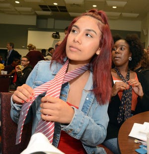 Dulce I. Tepetl Rojas, left, and Chavani Nelson learn to tie ties to go to a fantasy job interview Tuesday during Senior Seminar Lunch & Learn at NFA. At left is Katherine Cepeda. [John Shishmanian/ NorwichBulletin.com]