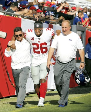 New York Giants running back Saquon Barkley (26) gets helped off the field after getting hurt against the Tampa Bay Buccaneers during the first half of a Sept. 22 game in Tampa, Florida. [Mark LoMoglio / Associated Press File]