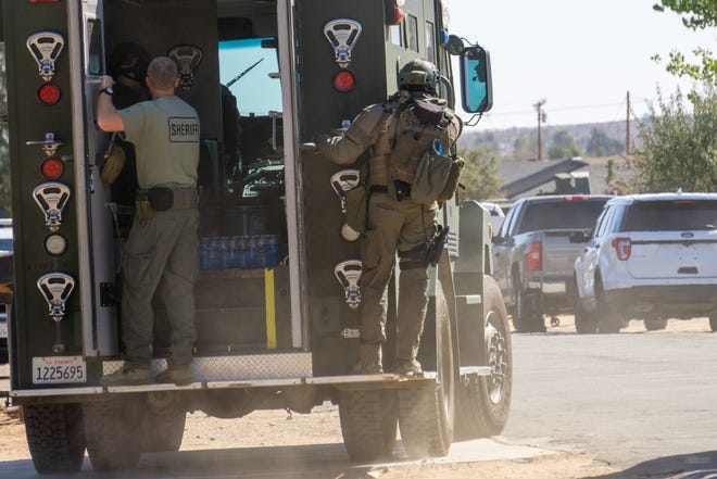 A San Bernardino County Sheriff's SWAT armored vehicle with two deputies holding on moves into a closer position on Tuesday in Apple Valley. [Martin Estacio, Daily Press]