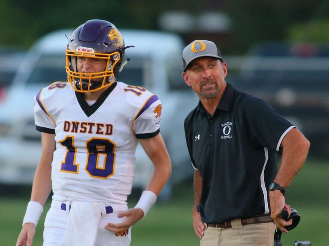 Onsted head football coach Dan Terryberry, right, talks to his son, junior quarterback Dylan Terryberry, during the Wildcats game against Blissfield earlier this season.