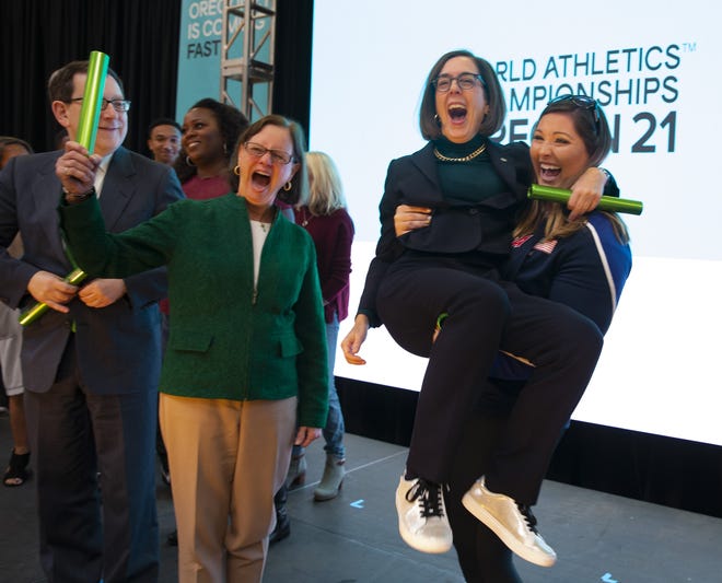 IAAF World Championship gold medal winner DeAnna Price, right, lifts Oregon Gov. Kate Brown in the air at the end of the kickoff event for Oregon21 at the University of Oregon, with UO President Michael Schill, left, and Eugene Mayor Lucy Vinis, center. [Chris Pietsch/The Register-Guard] - registerguard.com