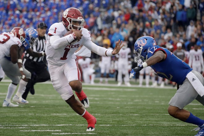 Oklahoma quarterback Jalen Hurts (1) gets past Kansas safety Jeremiah McCullough (12) during last week's game in Lawrence. [ASSOCIATED PRESS]