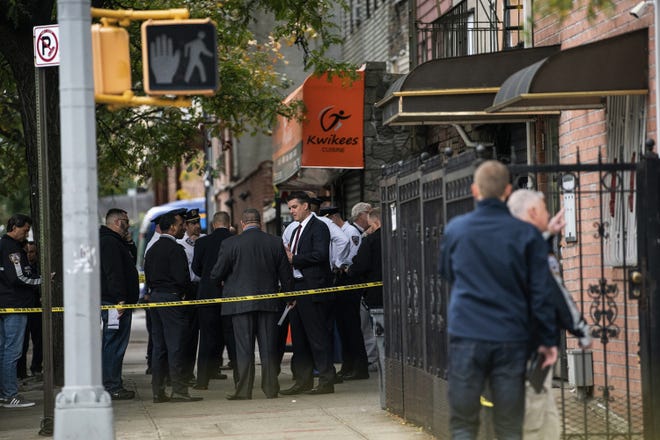 NYPD investigates the scene of a shooting in the Brooklyn borough of New York on Saturday. Authorities responded to a call about shots fired just before 7 a.m. and found four men dead in the Crown Heights neighborhood of Brooklyn at an address that corresponds to a private social club according to an online map of the street. A woman and two men suffered non-life-threatening injuries. [JEENAH MOON/THE ASSOCIATED PRESS]