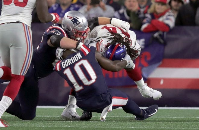 The Patriots Josh Gordon (10) twists his left leg as Giants linebacker Markus Golden fights for the ball. Gordon is one of many Patriots dealing with injuries.