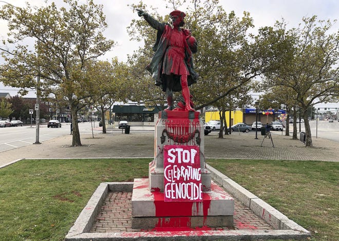 A sign reading "stop celebrating genocide" sits at the base of a statue of Christopher Columbus on Monday, Oct. 14, 2019, in Providence, R.I., after it was vandalized with red paint on the day named to honor him as one of the first Europeans to reach the New World. The statue has been the target of vandals on Columbus Day in the past. (AP Photo/Michelle R. Smith)