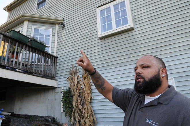 David Fernandes points to the second-floor window that was struck Monday by a stray bullet at his parents' West Bridgewater Lincoln Street home, Tuesday, Oct. 15, 2019. His two young girls -- Sofia, 2, and Adelina, 3 -- were playing at a children's table underneath the window when the bullet entered the home on Monday afternoon. No one was injured. (Marc Vasconcellos/The Enterprise)