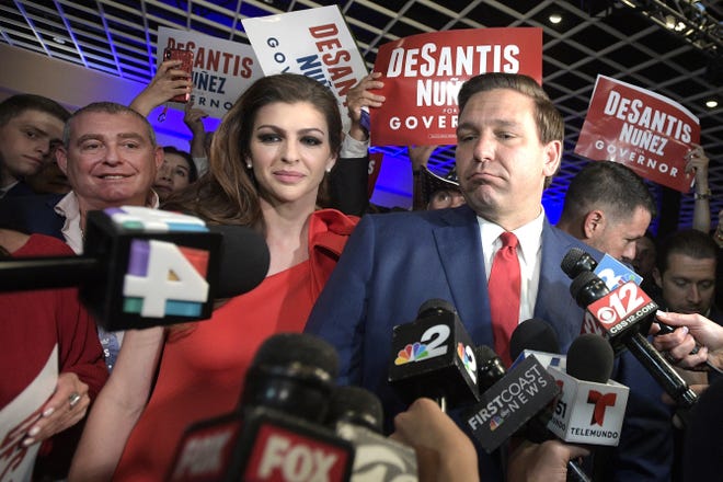 In this Nov. 6, 2018, file photo, Florida Governor-elect Ron DeSantis, right, answers questions from reporters, with his wife Casey, after being declared the winner of the Florida gubernatorial race at an election party, in Orlando. Standing behind Casey DeSantis is Lev Parnas. Parnas and his associate Igor Fruman are facing federal charges in connection to efforts by President Donald Trump's lawyer, Rudy Giuliani, to launch a Ukrainian corruption investigation against Joe Biden and his son, Hunter. [Phelan M. Ebenhack/The Associated Press/File]
