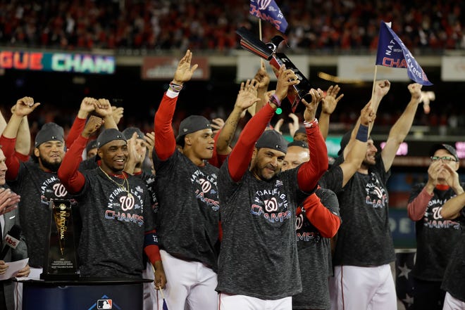 Washington Nationals manager Dave Martinez raises the NLCS trophy after Game 4 of the baseball National League Championship Series against the St. Louis Cardinals Tuesday, Oct. 15, 2019, in Washington. The Nationals won 7-4 to win the series 4-0. (AP Photo/Jeff Roberson)