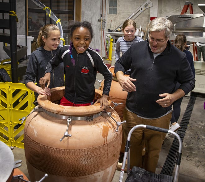 Ten-year-old Jazzy Lynn-Skov, center left, reacts as her toes sink into the wine grapes inside a fermentation pot at Civic Winery as owner Craig Weicker supervises the grape stomping stage of the wine making process at right. [Chris Pietsch/The Register-Guard] - registerguard.com