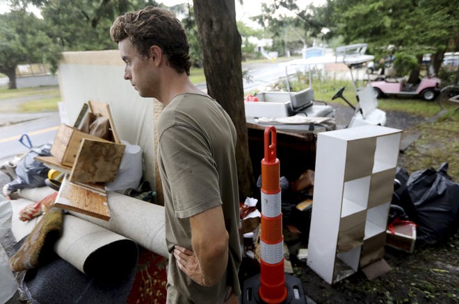 Christian Maybry stands near a pile of flood-damaged furniture and rugs at his Ocracoke home on Monday, Sept. 9, 2019. Hurricane Dorian brought historic flooding to the island. (Steve Earley/The Virginian-Pilot via AP)