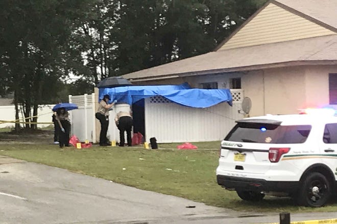 Crime scene investigators with the Marion County Sheriff's Office work in the rain at the scene of a death investigation in the Whispering Sands community southeast of Ocala on Friday afternoon. [Austin L. Miller/Staff]