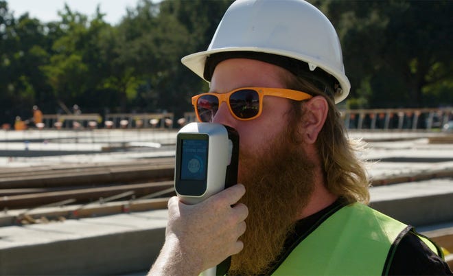 Hound Labs, backed by Philadelphia hedge fund Intrinsic Capital Partners, expects to launch a breathalyzer in early 2020 that can detect whether someone has consumed marijuana in the last three hours. In this photo, a construction worker blows into the handheld device. [Hound Labs]