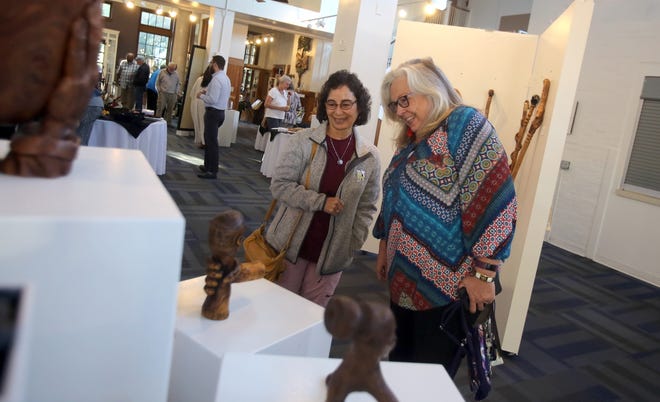 From left, Cindi Dashnaw and Jeanne Adkins enjoy pieces created by the late Frank Barrow at the Cleveland County Arts Council on Thursday. [Brittany Randolph/The Star]
