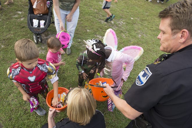 Savannah police Capt. Michelle Halford and Capt. David Gay hand out candy to trick-or-treaters at the department's third annual Pumpkin Painting with Police event on Thursday at Daffin Park. [Will Peebles/Savannahnow.com]