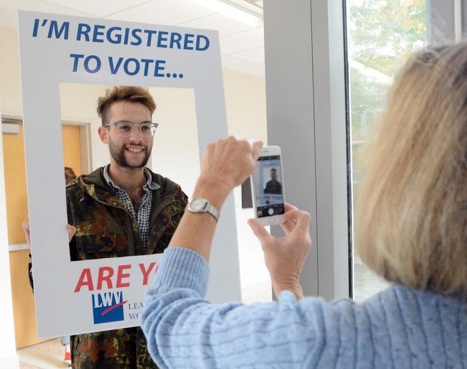 Michael Nenes, 24, of Montville (who is already a voter) has his photo taken by Janet Johnson, of Stonington, a League of Women Voters member, Thursday during voter registration at Three Rivers Community College in Norwich. [John Shishmanian/ NorwichBulletin.com]