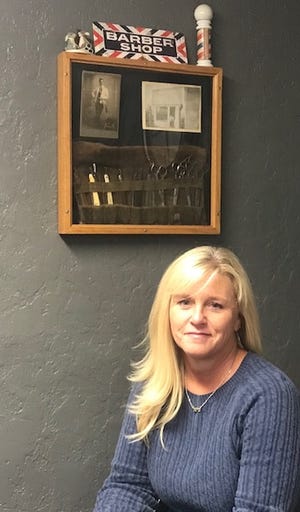 Pictured is Michelle Mozena, owner of The Hairport Barber Shop and Salon in Newcomerstown. Michelle is pictured in front of her late great-grandfather Wil Starts' collection of barber items he used in the early 1900s at his barber shop that was located on River Street in Newcomerstown. She was given these gifts from her late grandmother — Vodean Bryan (Wil's daughter) upon her graduation from barber school. (TimesReporter.com/Kristie Wilkin)