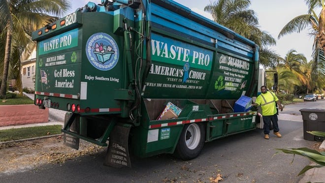 Amos Edmund of Waste Pro picks up recycling bins in front of a home on September 15, 2017. (Greg Lovett / The Palm Beach Post)