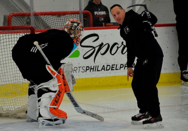 Flyers skills coach Angelo Ricci (right) works with goaltender Brian Elliott during Tuesday's practice at the Skate Zone. [ZACK HILL / FLYERS]