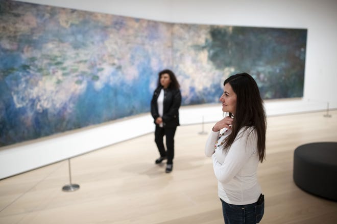 Liz Bejarano, right, and her mother, Beatriz Cautillo, view Claude Monet's “Water Lilies” at the Museum of Modern Art in New York City. The museum reopened to the public on Sunday after a four-month, $450 million renovation. [Karsten Moran/The New York Times]