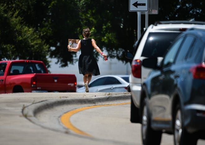 A woman holds a sign that reads "Have a wonderful day" as she panhandles from the median at the intersection of 44th Avenue East and U.S. 41 in Bradenton. On Tuesday, the Manatee County Commission passed an ordinance that outlaws any transactions between pedestrians and occupants of motor vehicles in public roadways. [Herald-Tribune staff photo / Dan Wagner]