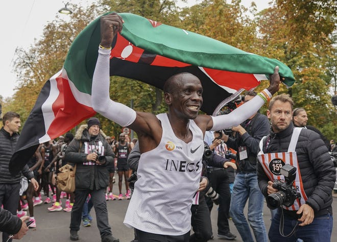 Eliud Kipchoge celebrates with the Kenyan flag after breaking the historic two-hour barrier for a marathon in Vienna on Oct. 12. [JED LEICESTER / ASSOCIATED PRESS]
