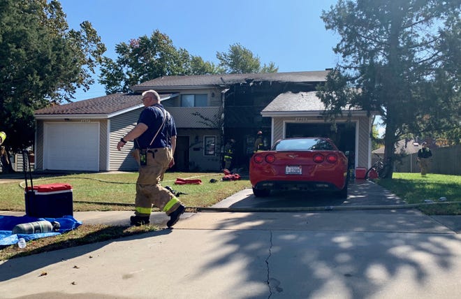 Topeka fire crews battle a blaze Tuesday afternoon at a two-story structure containing a pair of townhomes in the 5400 block of S.W. 23rd Street. Firefighters backed a red Chervolet Corvette out of the garage after the blaze had been brought under control. [Phil Anderson/The Capital-Journal]