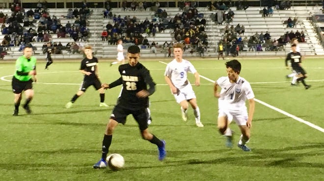 Topeka High senior Ernesto Garcia-Retana (26) tries to control the ball as Washburn Rural senior Trystan Cheung (1) defends Tuesday night in Rural's 4-0 Centennial League win over the Trojans at Hummer Sports Park. [Rick Peterson/The Capital-Journal]