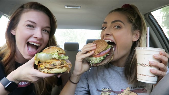This image made from video released by Brittany Marsicek shows dancer-actor Marsicek, 28, left, and actor Chantal Plamondon, 27, during the filming of their Mukbang Monday channel. The two focus on vegan food, reviewing the latest fast-food offerings, and often film in their cars as they chat about auditions and day jobs while munching from fast-food containers. (Brittany Marsicek via AP)